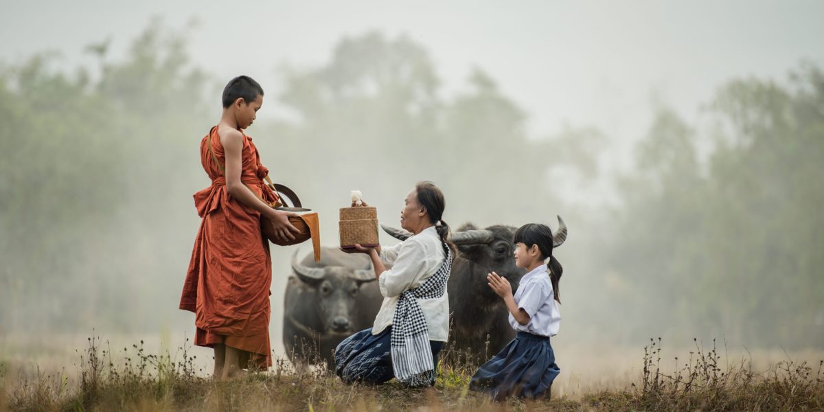 Grandmother and grandson offer food to the novices