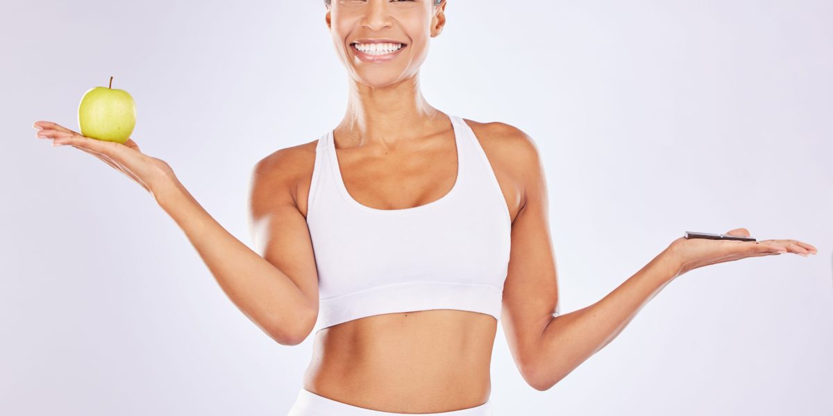Portrait, apple or happy woman with chocolate choice in studio for a healthy snack, diet nutrition .