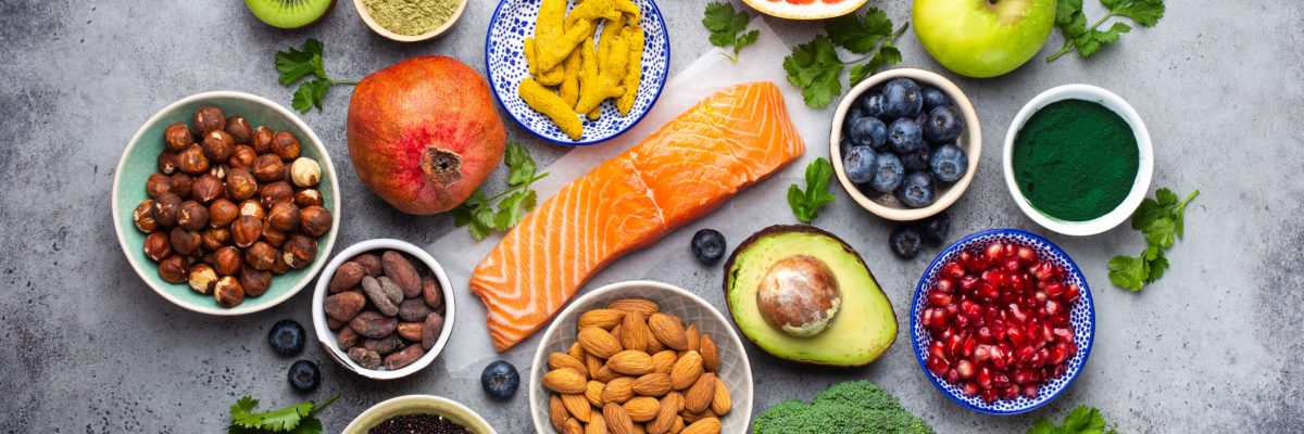 Selection of healthy products and superfoods: salmon, fruit, vegetables, berries, goji, spirulina, matcha, quinoa, chia seeds, nuts. Clean eating concept, gray background, top view, close up